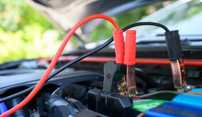 Professional jump start cables connected to a dead car battery in Qatar — AAQATAR roadside service